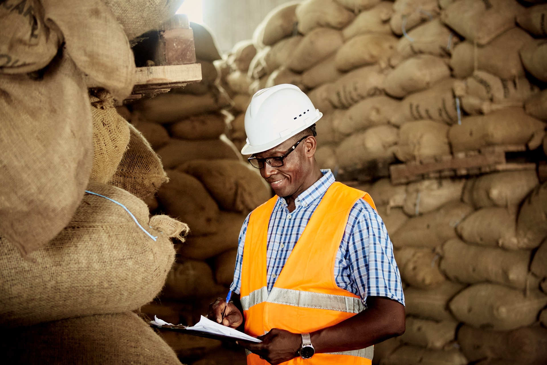 Mercy Trading inspector checking stacked sacks of cashew nuts
